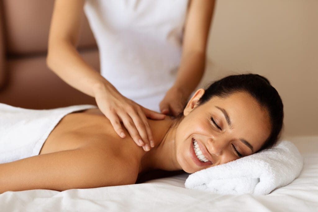 Mujer sonriendo relajada durante masaje relajante en camilla — beneficios físicos y emocionales