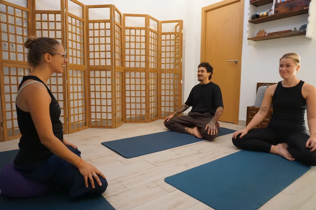 Amanda guiando una clase de yoga con alumnos sentados en sus esterillas en Quiroesencia, Granada